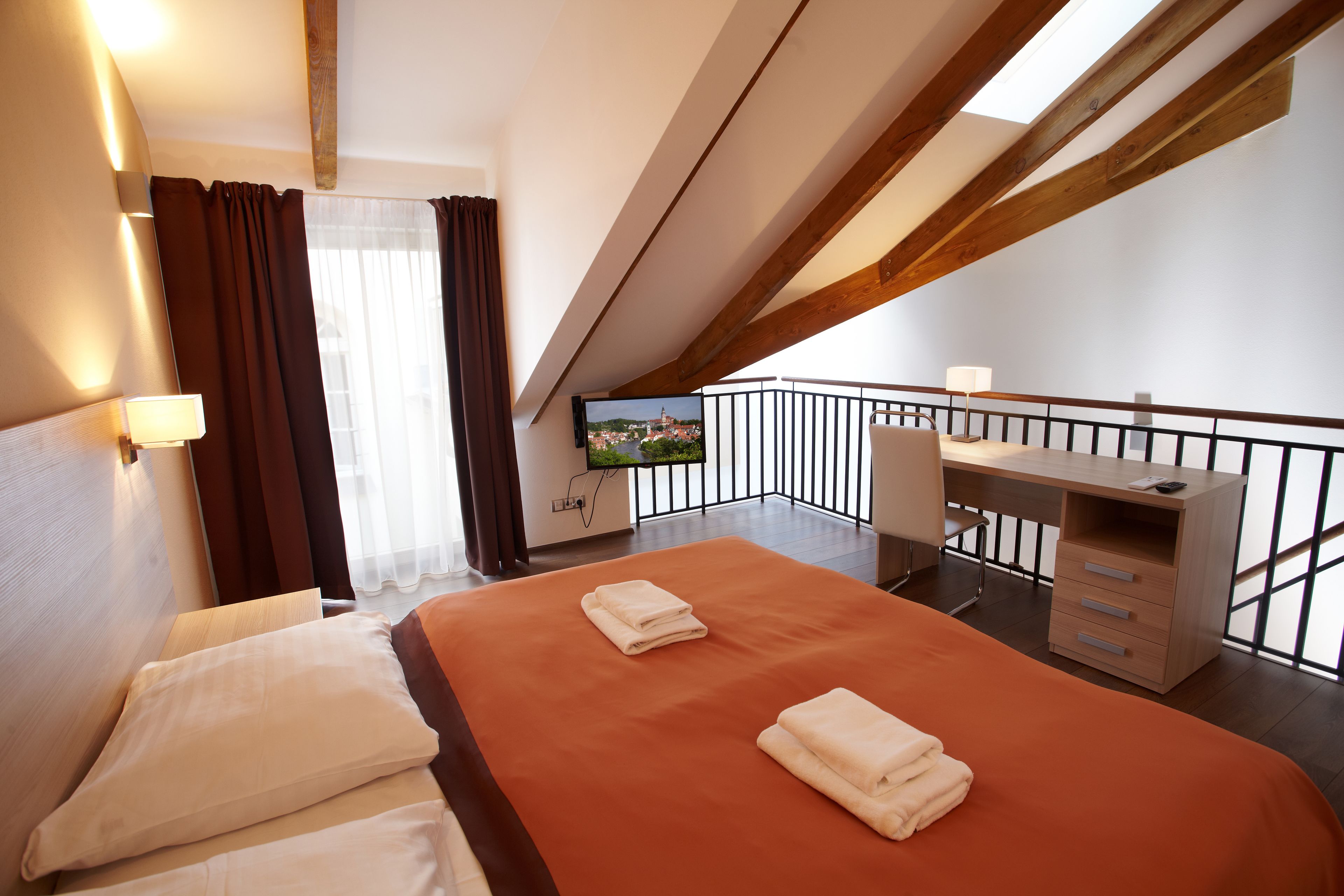 A hotel room with a bed, a desk, and a TV.