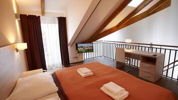 A hotel room with a bed, a desk, and a TV.