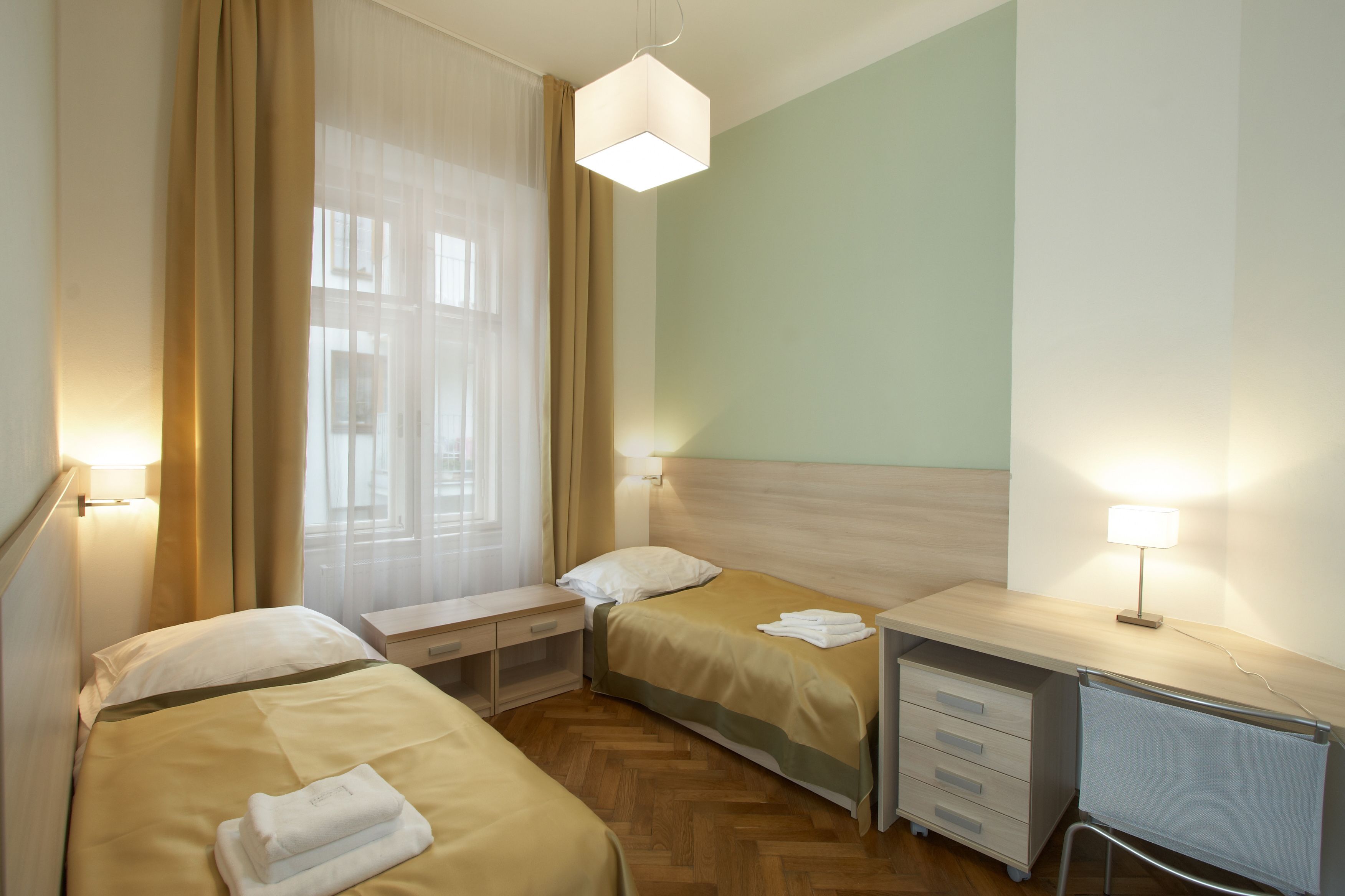 A hotel room with two beds, a desk, and a chair.