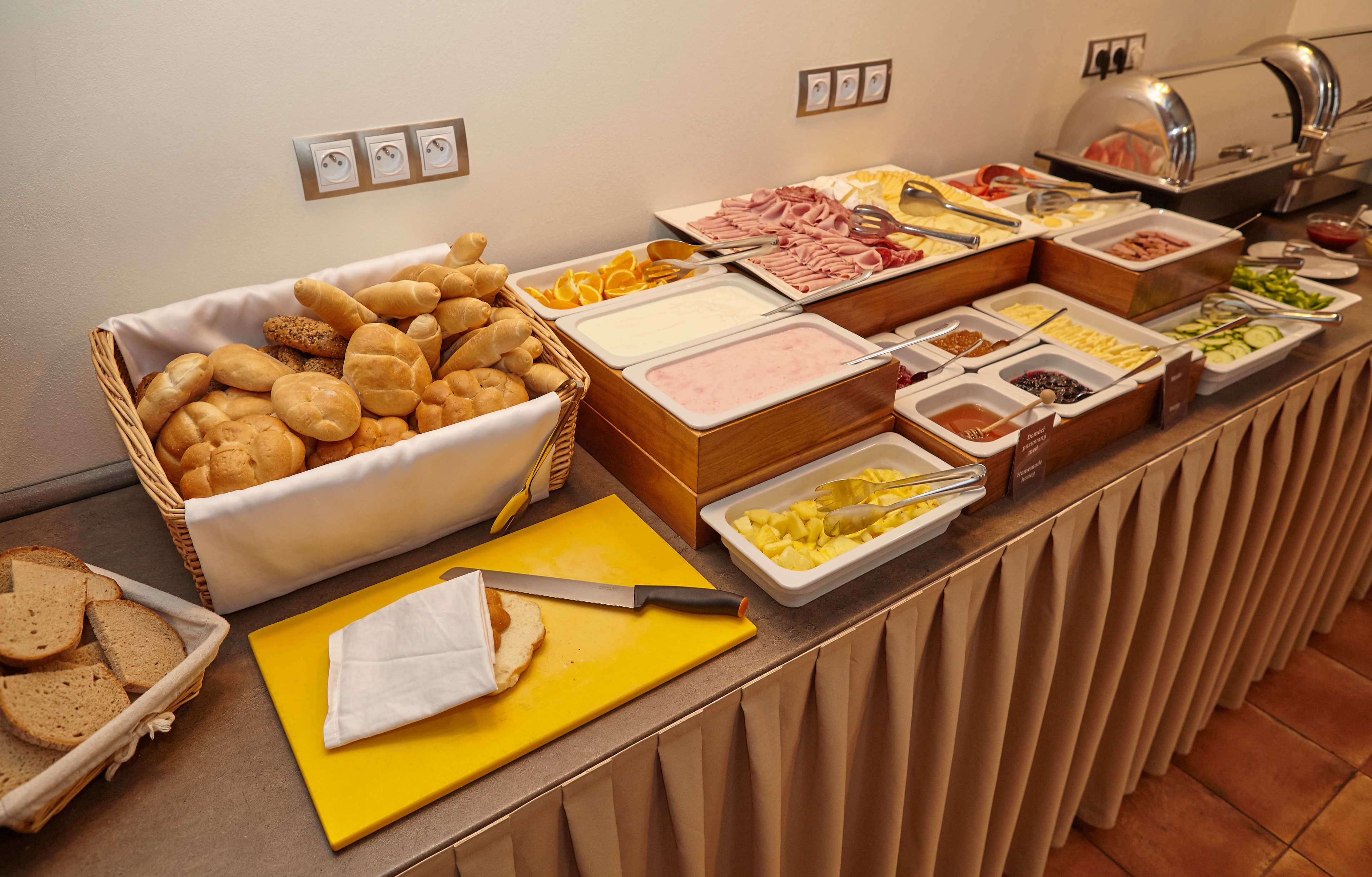 Un buffet proposant une variété d’aliments, notamment du pain, des fruits et de la viande.