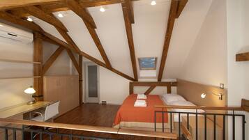 Un dormitorio con techo de madera, una cama, un escritorio y una silla.