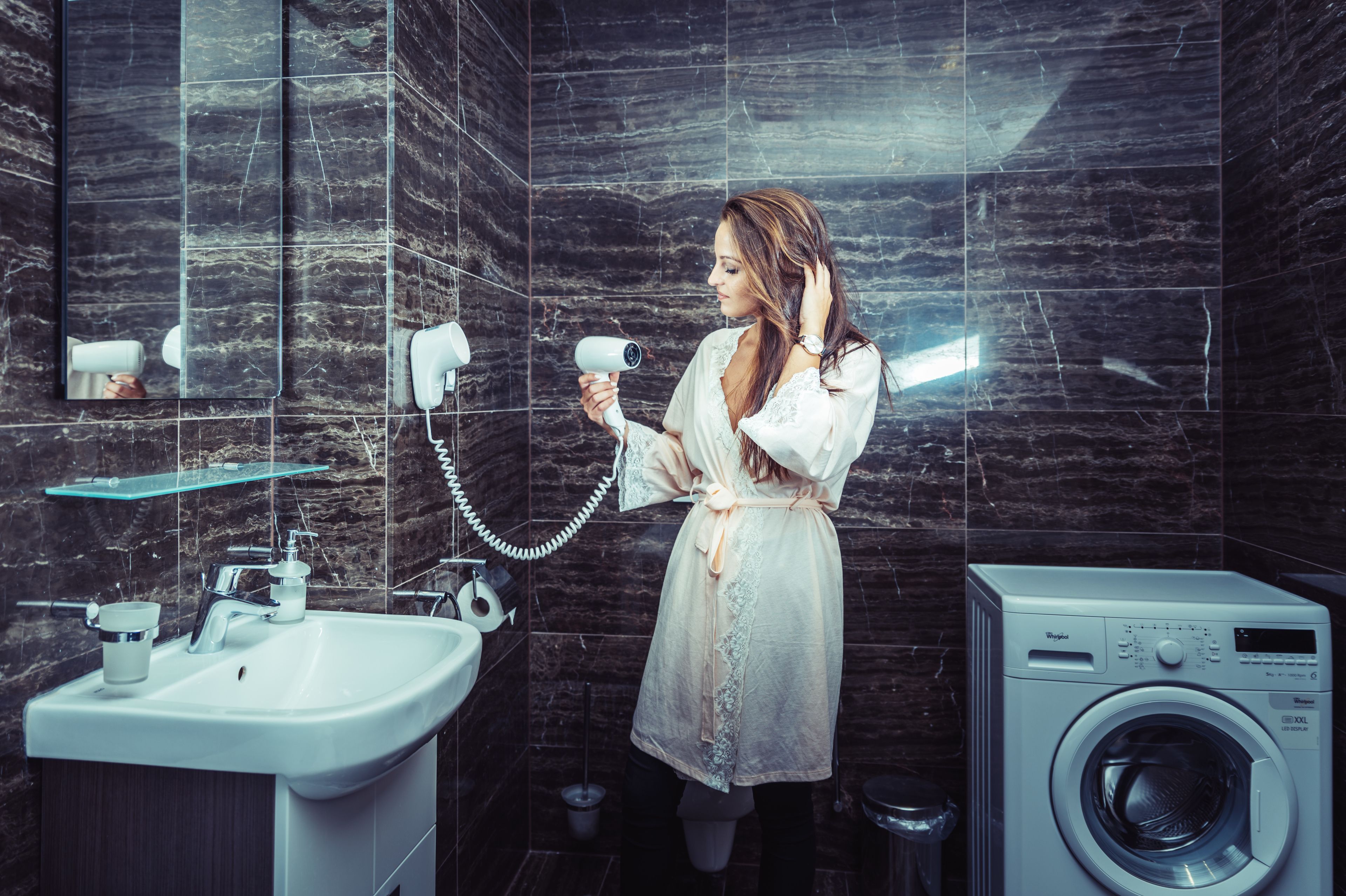 Ein Badezimmer mit Waschbecken, Spiegel, Haartrockner und einer Waschmaschine.