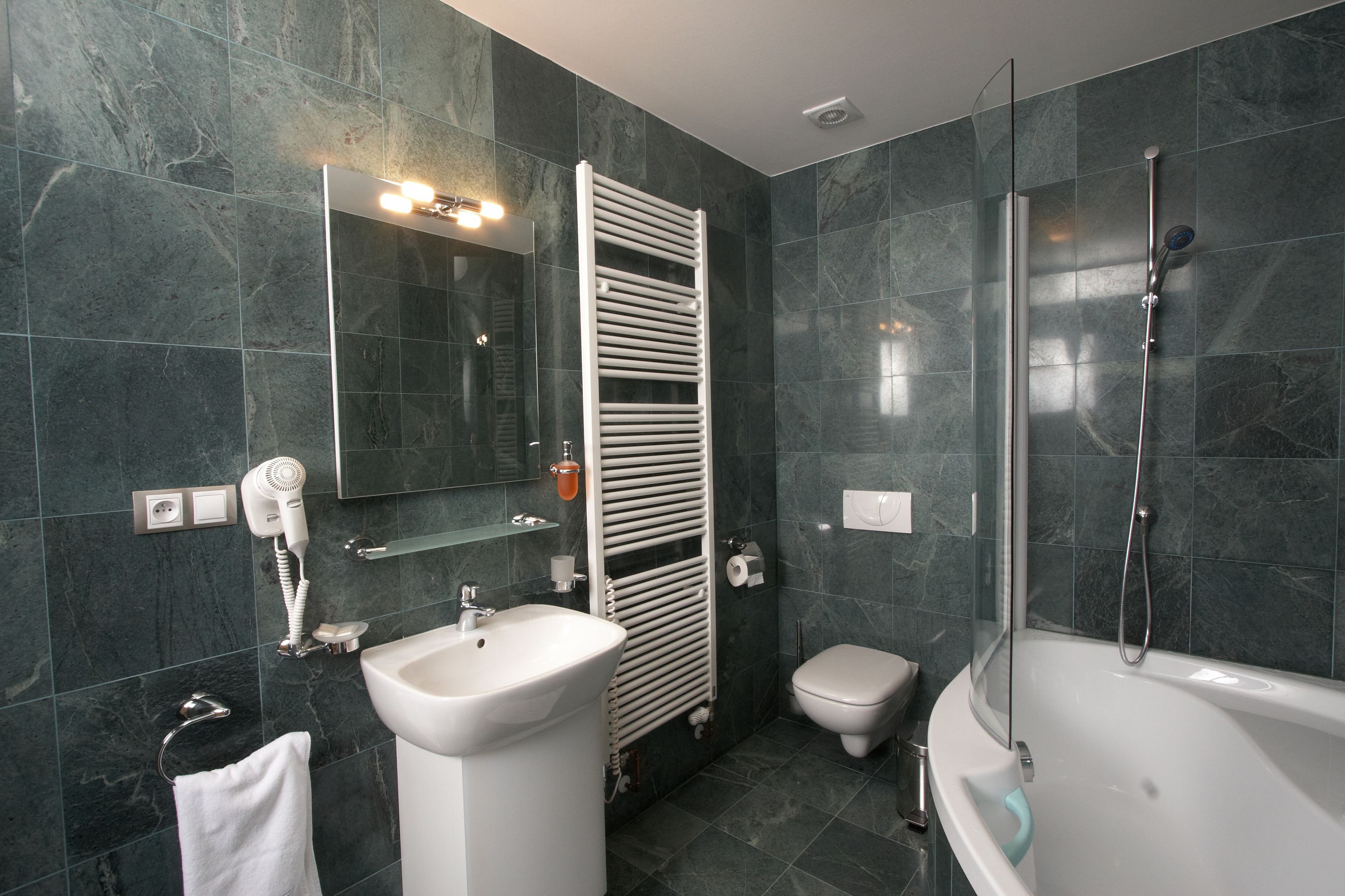 Een moderne badkamer met een ingebouwd wastafel, toilet, douche met glazen wanden en een handdoekhouder.