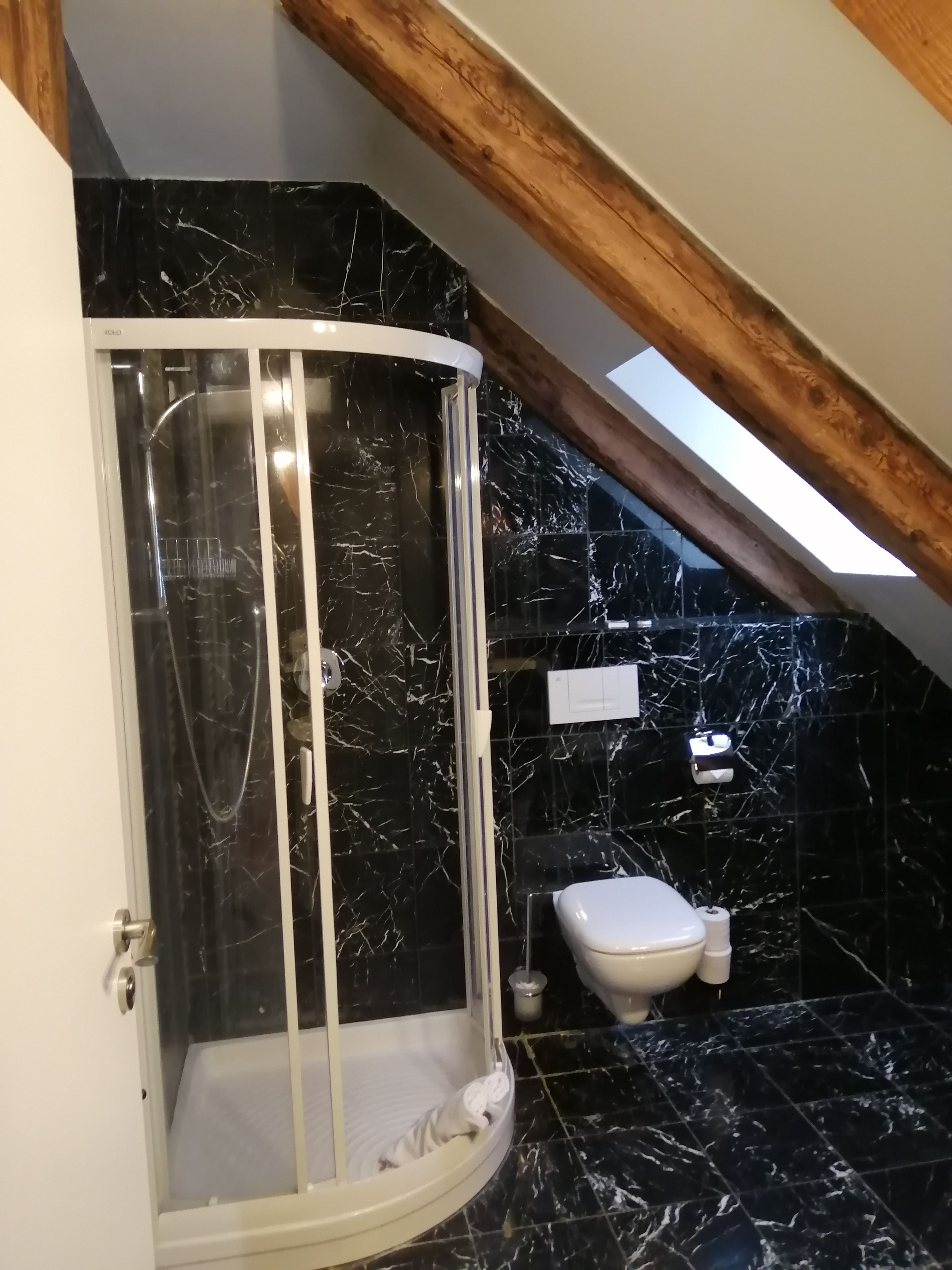 Un baño con cabina de ducha, inodoro y suelo de mármol.