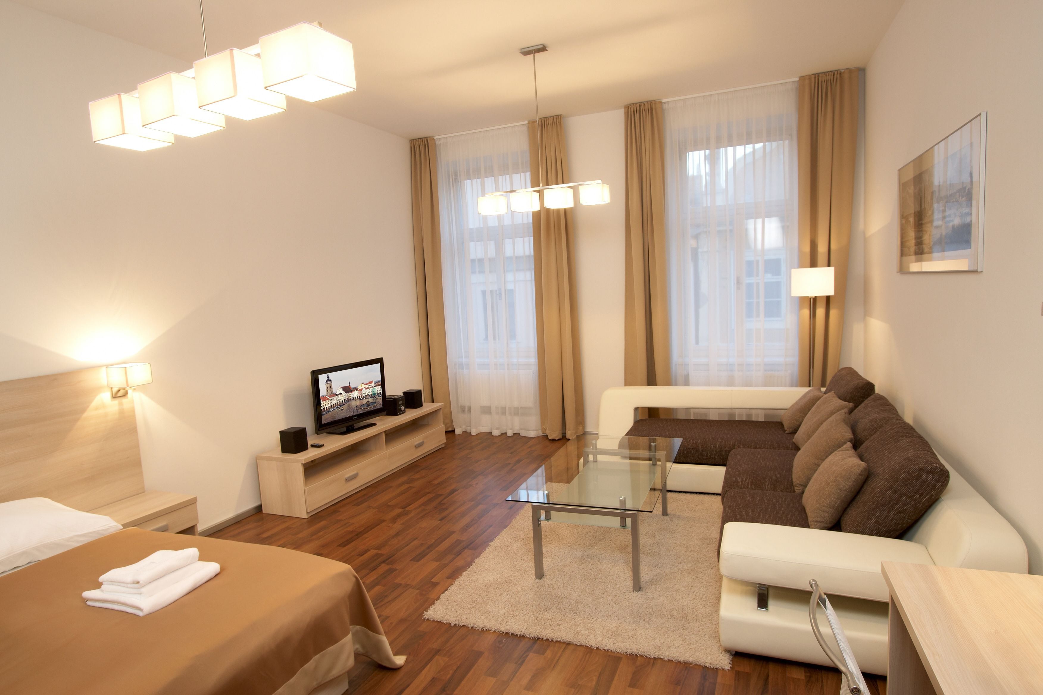 Una habitación de hotel moderna con cama, sofá, televisión y zona de comedor.