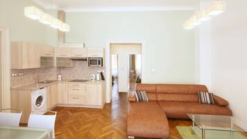 A modern kitchen with a washing machine, a microwave, and a dining area with a glass table.