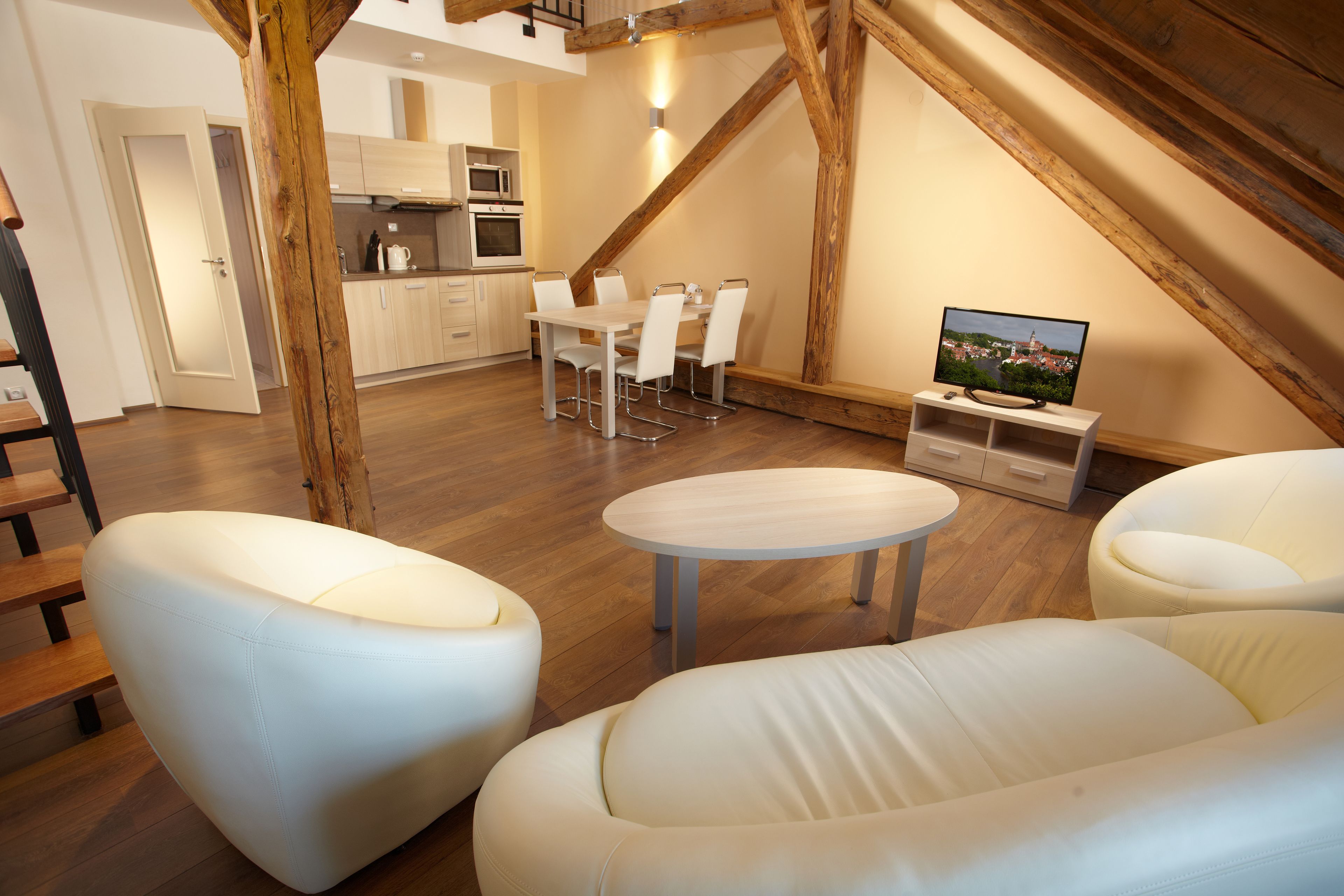 Un loft moderno con comedor, televisor y escalera.