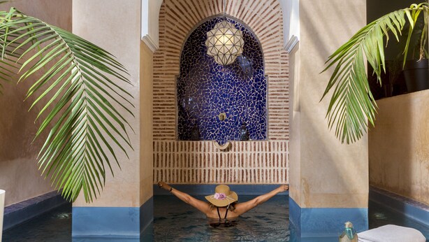 A spa pool with a tiled floor, a decorative archway, and a person relaxing in the water. - Riad Ines Home (Marrakech)
