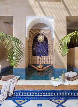 A spa pool with a tiled floor, a decorative archway, and a person relaxing in the water.