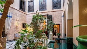 A courtyard with a tiled floor, a small pool, and potted plants. - Riad Ines Home (Marrakech)