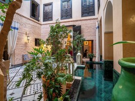 Un cortile con pavimento in piastrelle, una piccola piscina e piante in vaso.