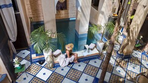 A poolside area with a tiled floor, a sitting area with a towel, and a view of the pool. - Riad Ines Home (Marrakech)