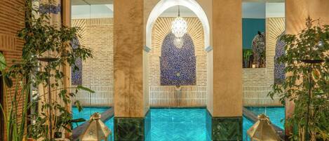 A pool area with a geometric tile design, a central archway, and lanterns.