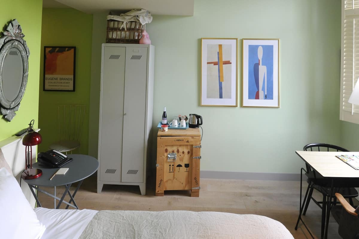 Una habitación de hotel con cama, escritorio, armario y radiador.