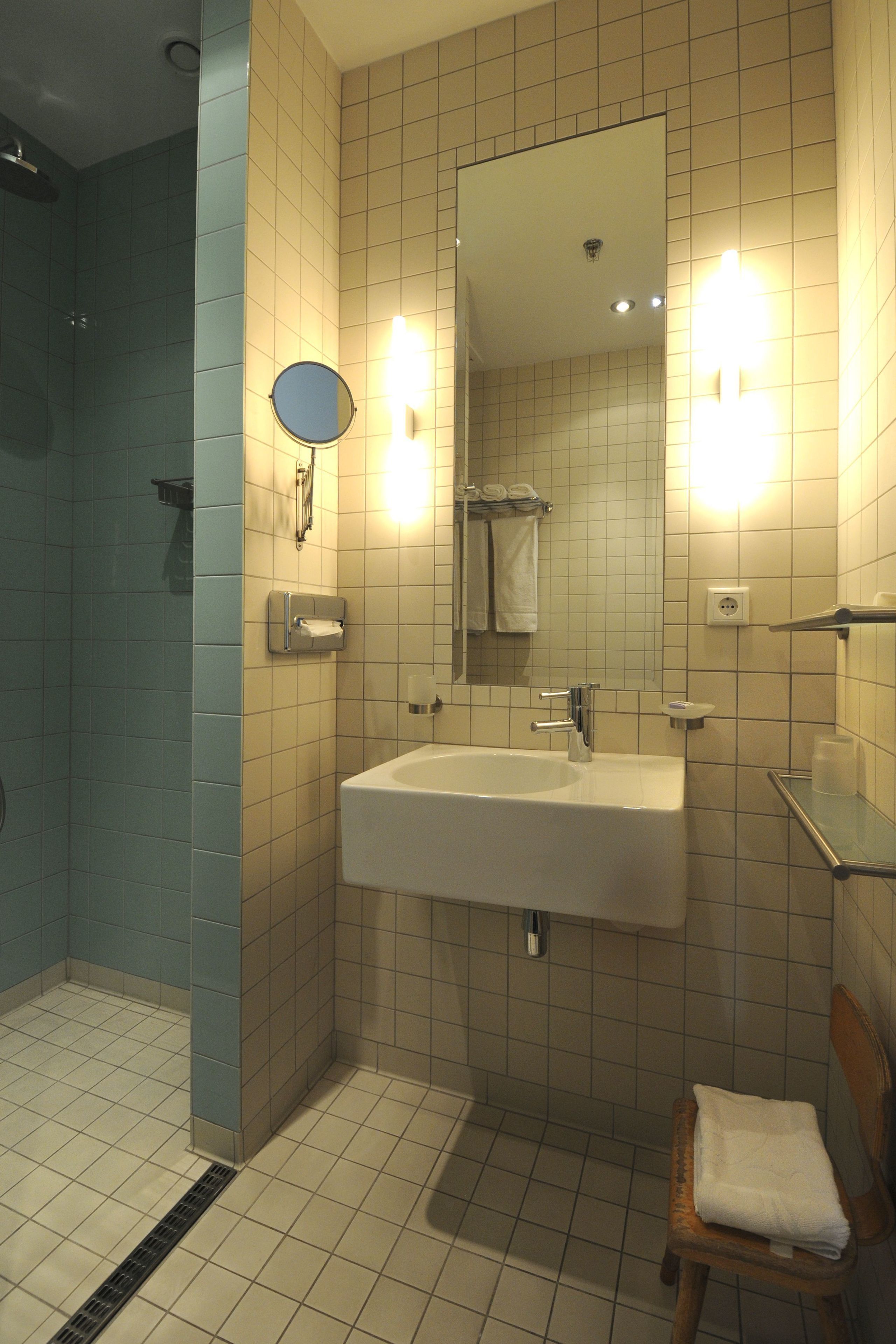 A bathroom with a sink, mirror, towel rack, and shower area.
