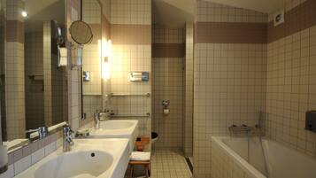 A bathroom with two sinks, a mirror, a shower, and a toilet.