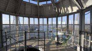 Una plataforma de observación en un edificio alto con amplias ventanas que ofrecen vistas de un puente y el horizonte de la ciudad.