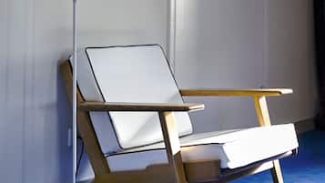Una habitación moderna con una silla de escritorio blanca, una lámpara de pie y una alfombra azul.