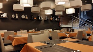 Un ristorante con tavoli apparecchiati per la cena, illuminazione a soffitto e una scala sullo sfondo.