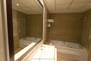 A modern bathroom with a large mirror, two separate tubs, and a sink.