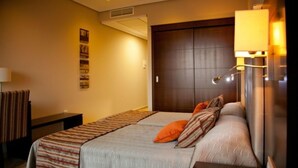 Una habitación de hotel con una cama grande, una mesita de noche, una lámpara y una obra de arte colgada en la pared.