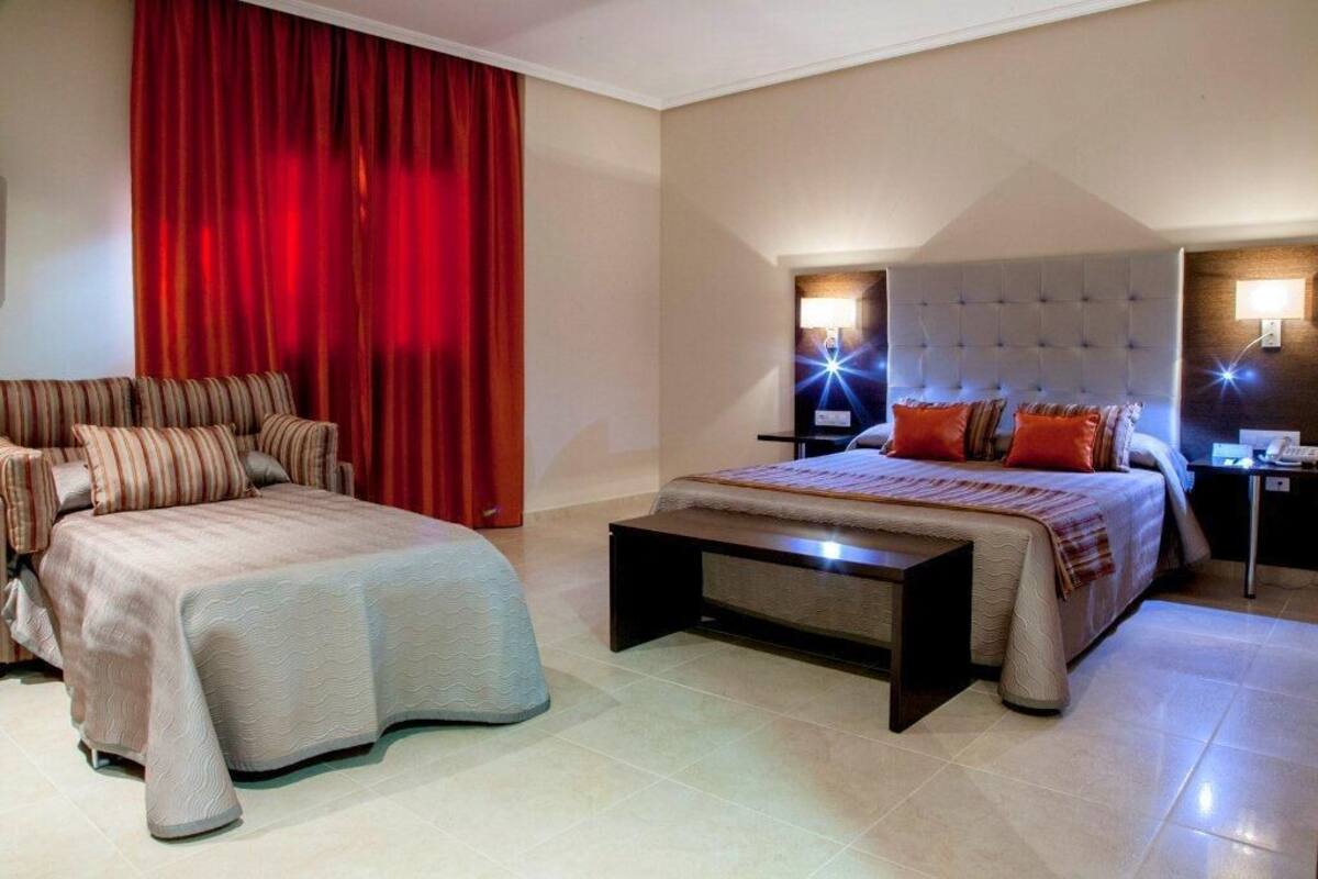 A hotel room with a bed, a sofa, a desk, and a nightstand.