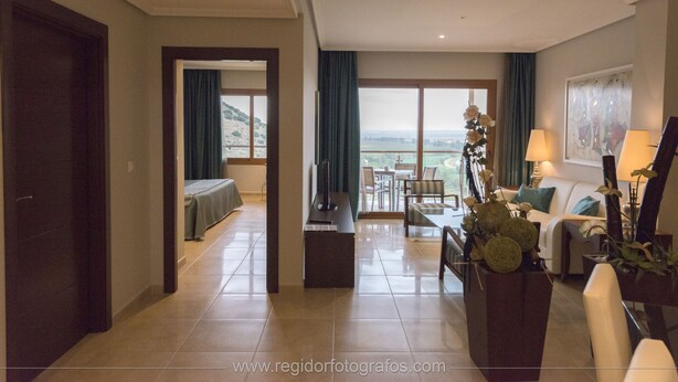 Una habitación de hotel con balcón, zona de comedor y sala de estar.