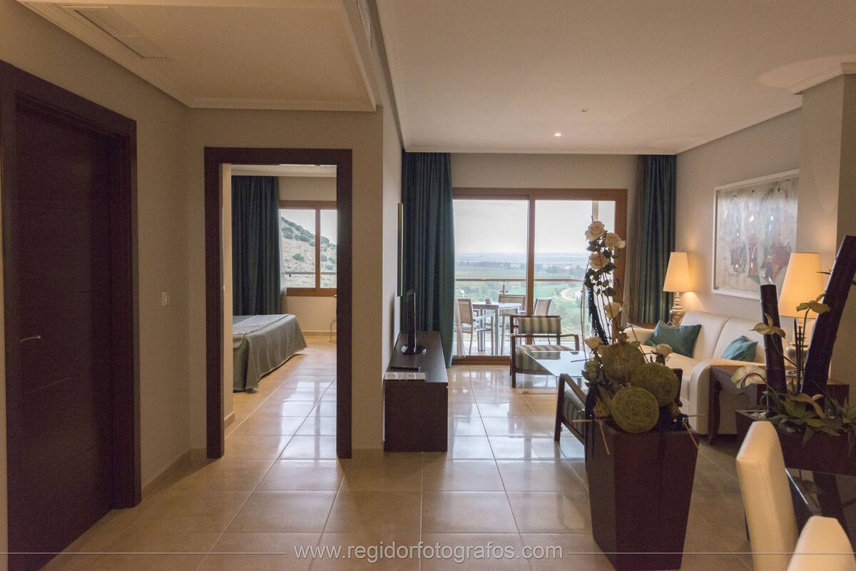 A hotel room with a balcony, a dining area, and a living room.