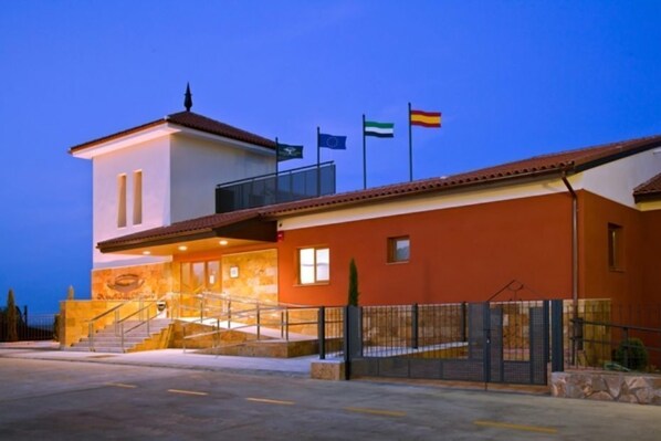 A hotel with a white and orange facade, a balcony, and multiple flags.