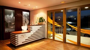 Un mostrador de recepción de diseño moderno, una planta en maceta y una puerta de vidrio que da al exterior.