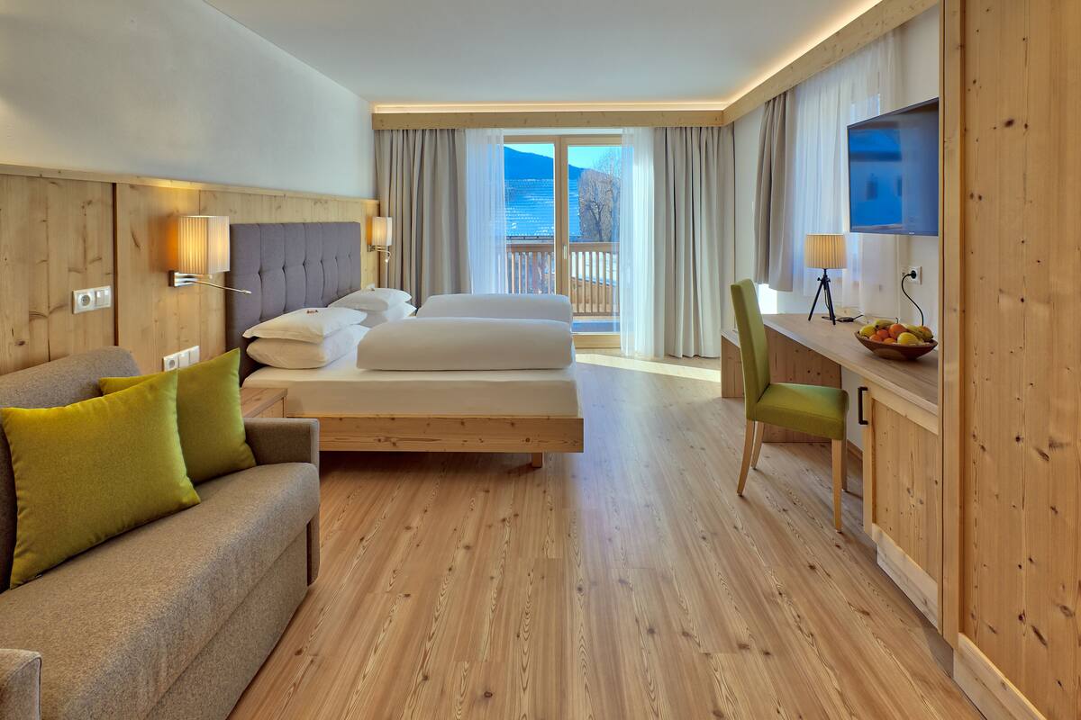 Ein Hotelzimmer mit einem Bett, einer Couch, einem Schreibtisch mit Stuhl und einem Fernseher.