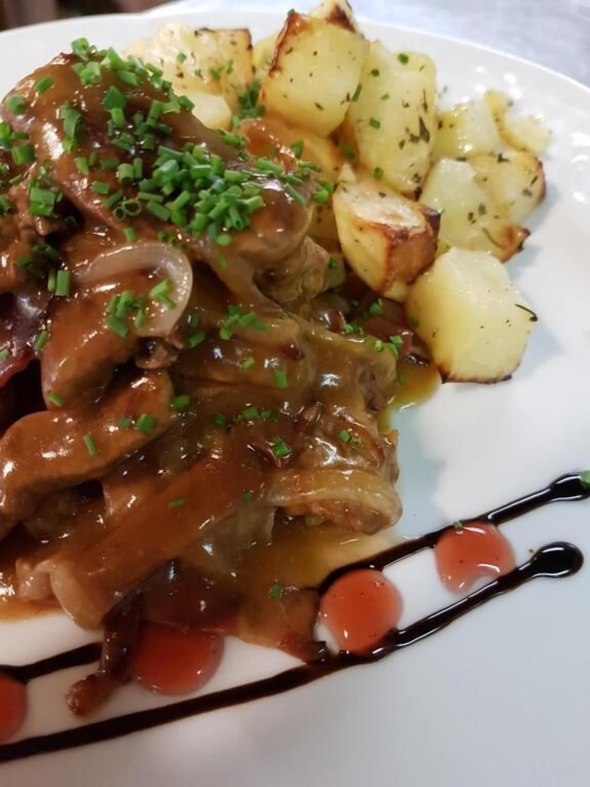 Ein Teller mit einem Fleischgericht, Kartoffeln und Soße.