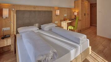 Ein Doppelbett mit Holz-Kopfteil, Nachttische mit Lampen, ein kleiner Schreibtisch mit Stuhl und ein Kleiderschrank.