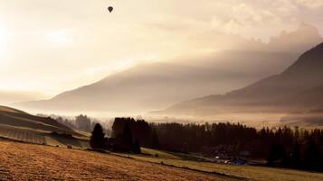 Paisaje rural con colinas ondulantes, cielo despejado y un globo aerostático a lo lejos.