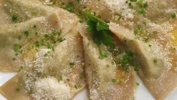 Un plato de ravioles adornado con queso rallado y hierbas picadas.