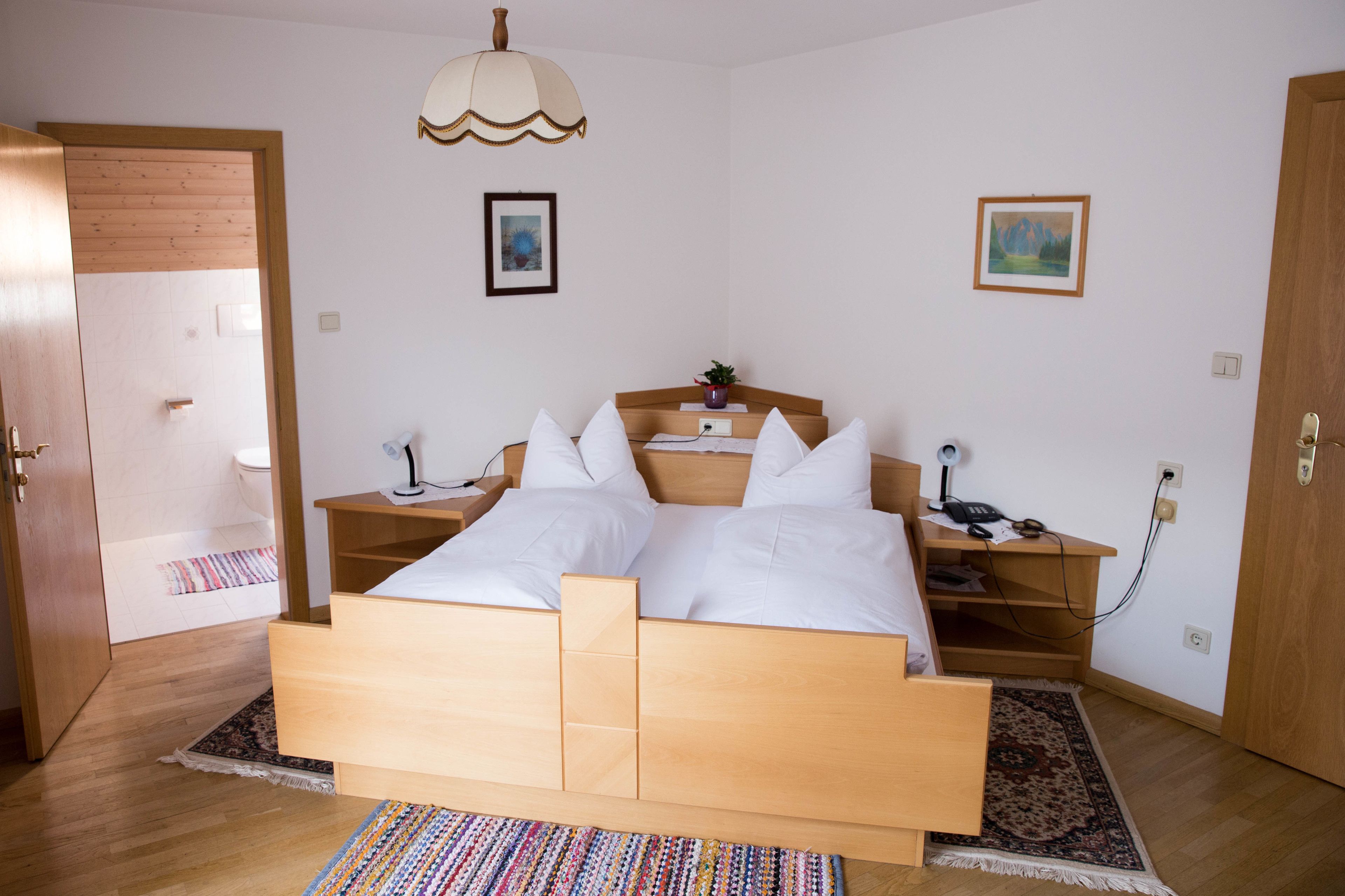 Ein Schlafzimmer mit einem Holzbett, Nachttischen, einer Lampe und einem Teppich.