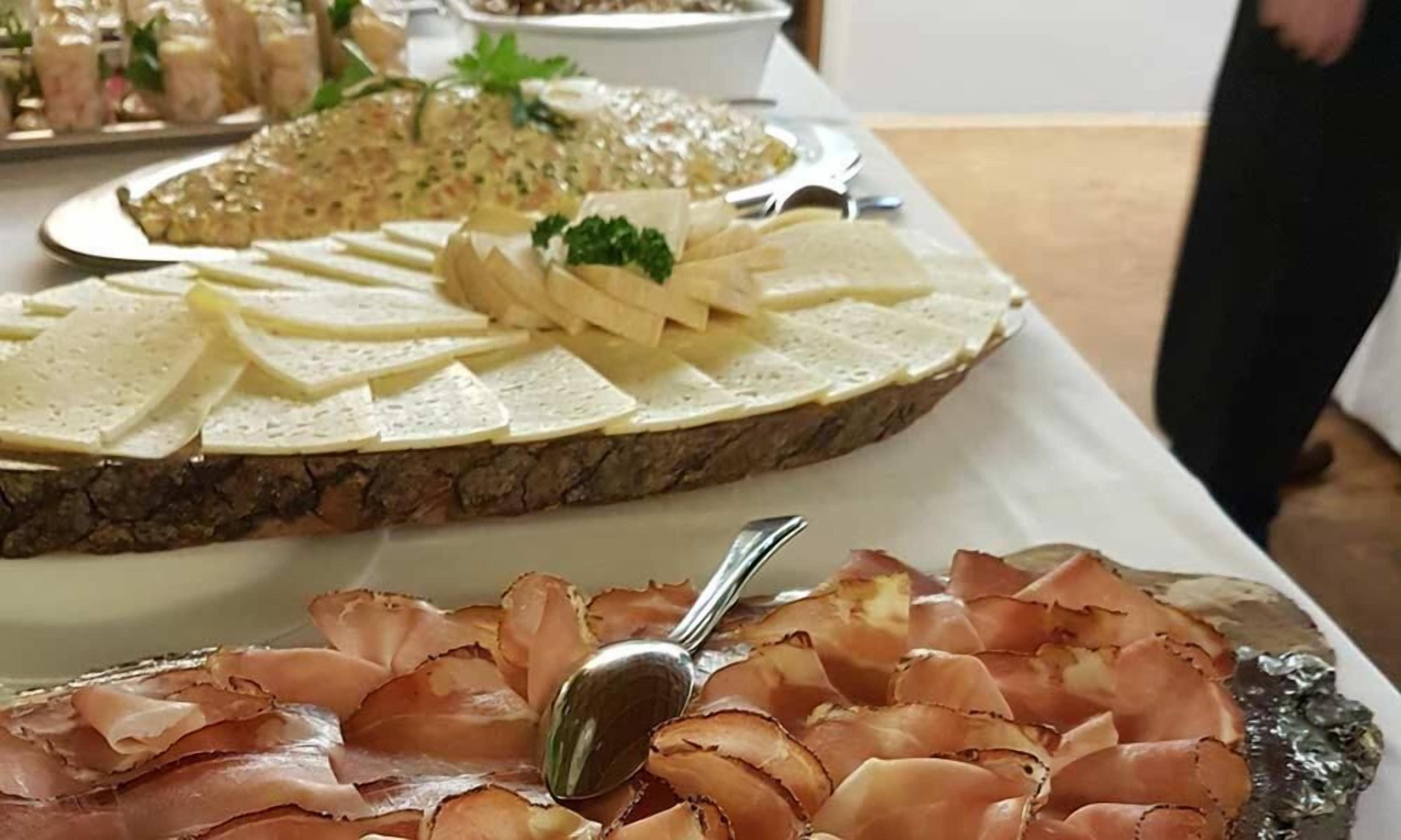 Noutopöytä, jossa on tarjolla monenlaista ruokaa, kuten viipaloitua leipää, juustolajitelma ja erilaisia kuivalihoja.
