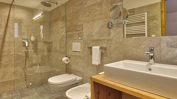 A modern bathroom with a shower, toilet, bidet, and a large sink.