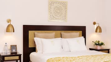 A hotel room with a bed, two bedside tables, a wall-mounted artwork, and two wall-mounted lamps.