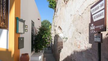 A narrow cobblestone street leading to a building with a sign for Esplanada Bar & Restaurante.