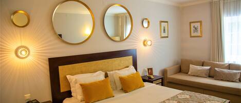 Una habitación de hotel con una cama grande, un sofá y varios espejos en la pared.