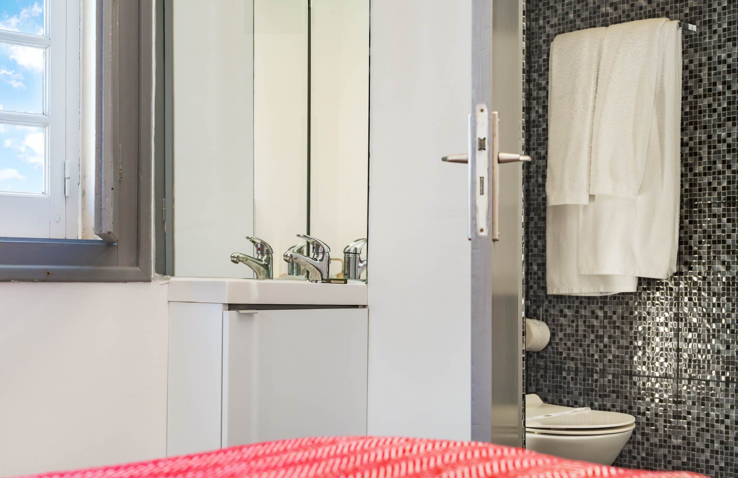 Ein Badezimmer mit Waschbecken, Spiegel und Toilette.
