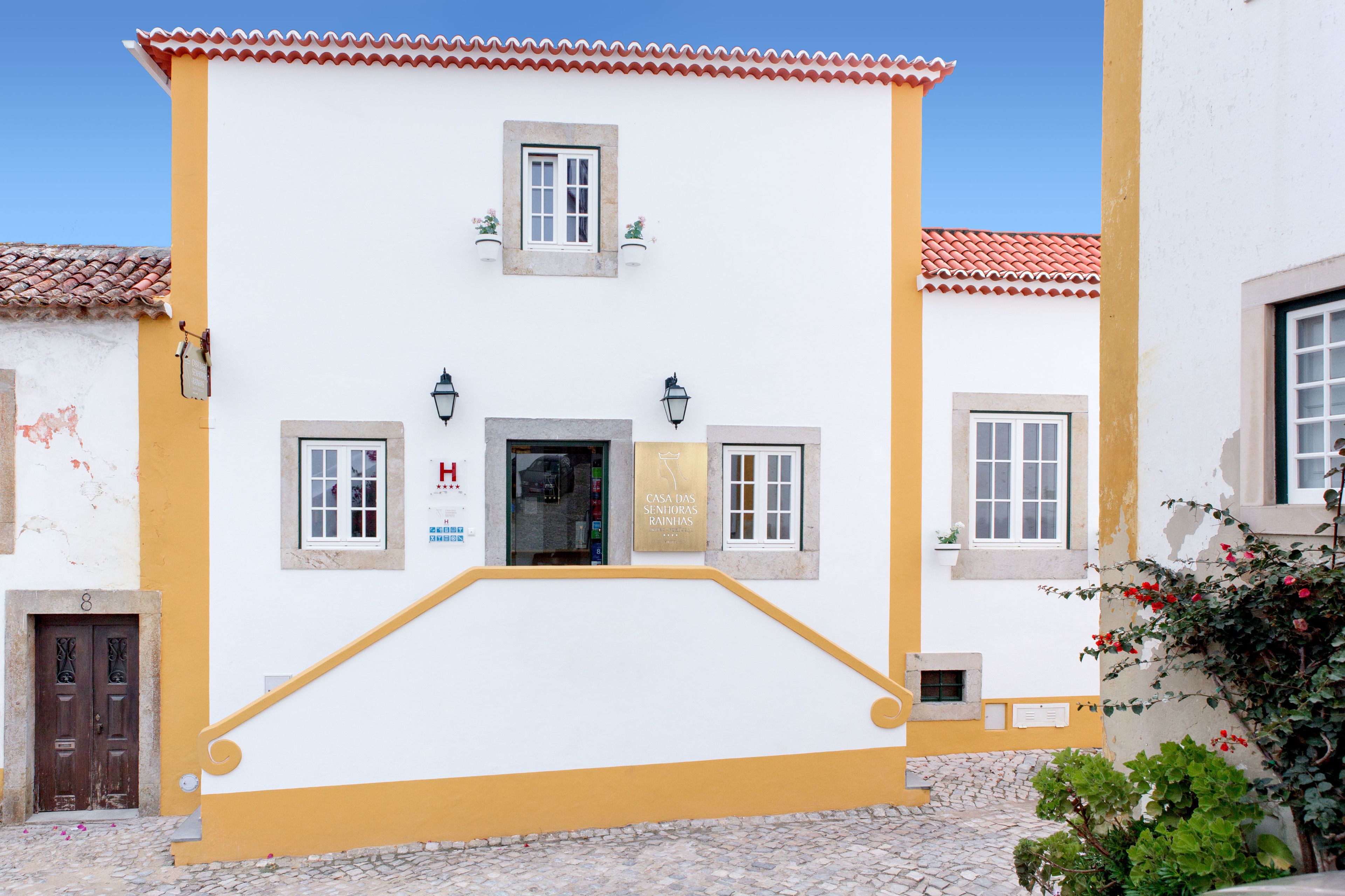 A building with a yellow facade, a central entrance, and a small window above the door.