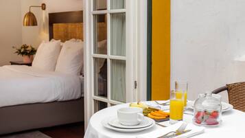 Habitación de hotel con cama, una mesa de comedor y desayuno, y vistas al exterior.