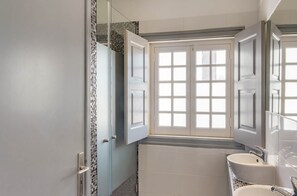Ein Badezimmer mit Fenster, Waschbecken und Spiegel.