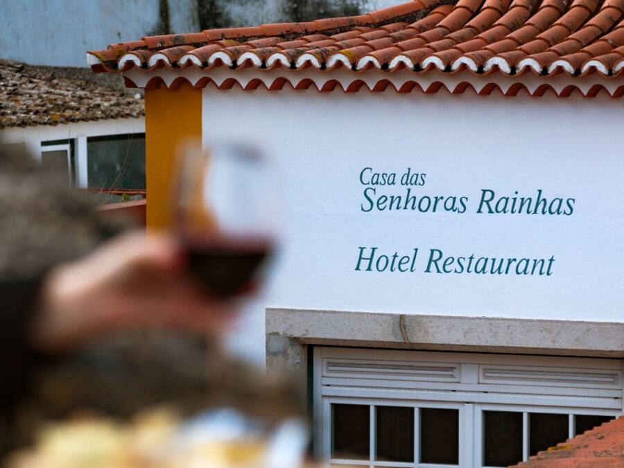 A building with a tiled roof and a sign that reads "Casa das Senhoras Rainhas Hotel Restaurant."