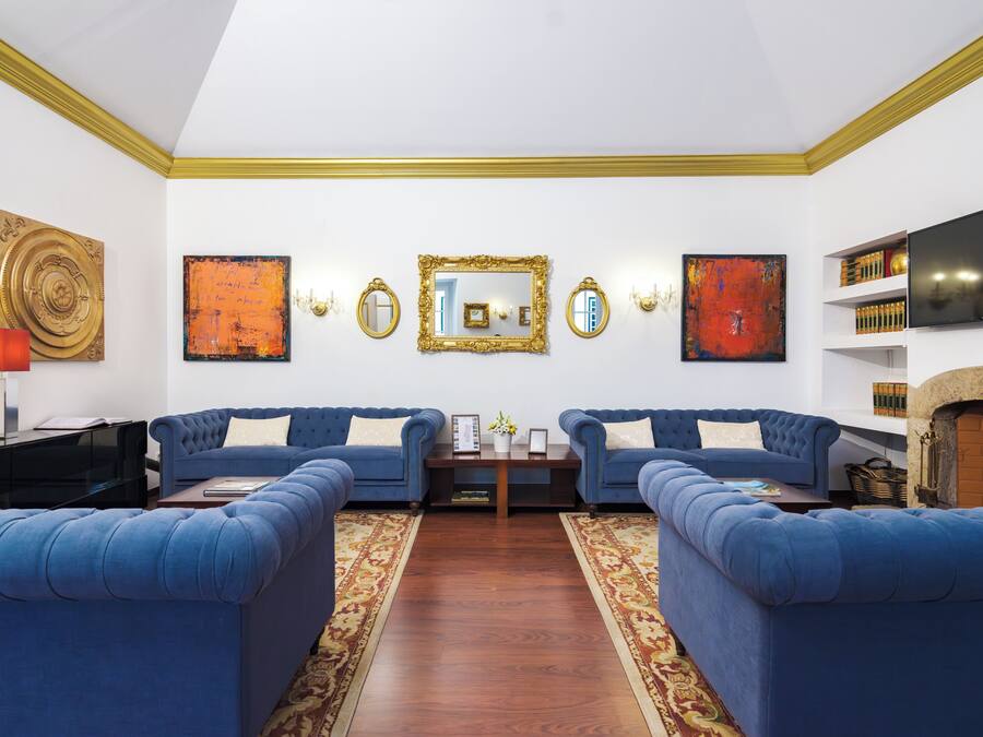 Een woonkamer met twee blauwe banken, een houten vloer en een open haard.