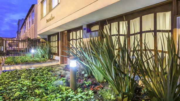 A hotel exterior with a well-maintained garden, large windows, and a sign reading "Hotel". - Hotel Portofino (Bogotá)