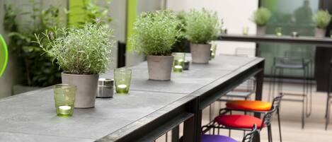 Una barra larga con plantas en macetas y vasos verdes sobre el mostrador.