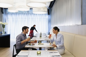 Ein Restaurant mit einem langen Tisch, gedeckt für ein Essen, einem Kellner im Hintergrund und einem modernen Innenraum.